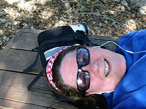 Laurie lies on her back on a bench at the top of the hiking trail