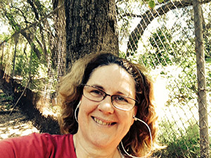 Laurie in a red t-shirt under a tree.