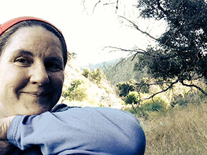 Laurie leaning her chin on her arm up in a grove on the hiking trail.