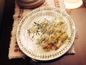 Scrambled eggs and veggies on a plate wrapped in clear film to be put into the refrigerator