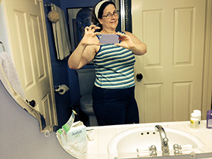 Laurie in the mirror wearing jeans and sleeveless top.