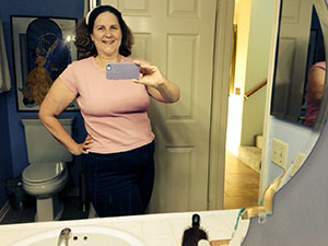 Laurie in a pink T-shirt and jeans viewed in a mirror.