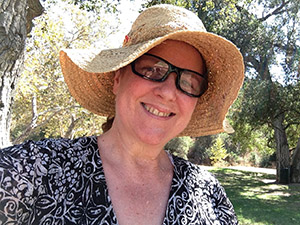 Laurie in a black print blouse and straw hat