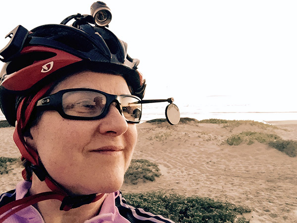 Laurie looking back via bike helmet mirror near the beach