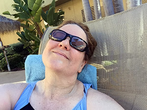 Laurie in a swimsuit in a chair by the pool