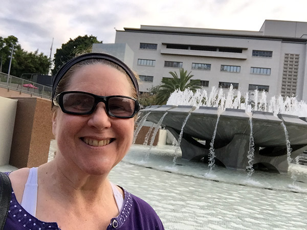 Laurie in front of a large outdoor fountain