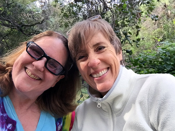 Laurie and Sandy in the grove of oak trees by the podcast rock