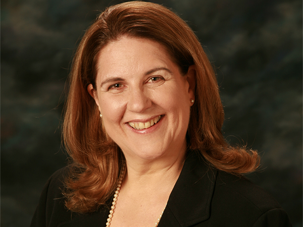 Laurie with styled long hair in suit and pearls - corporate headshot