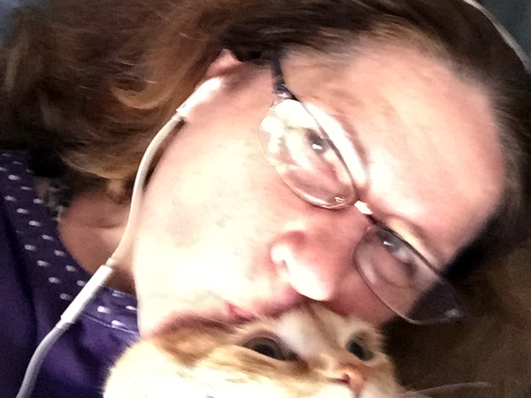 Laurie kissing Tiger, the orange cat's head