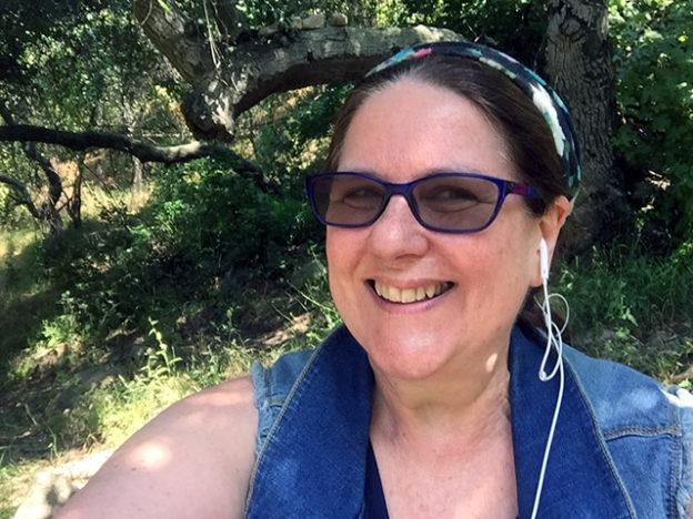 Laurie Smiling under a tree with glasses.